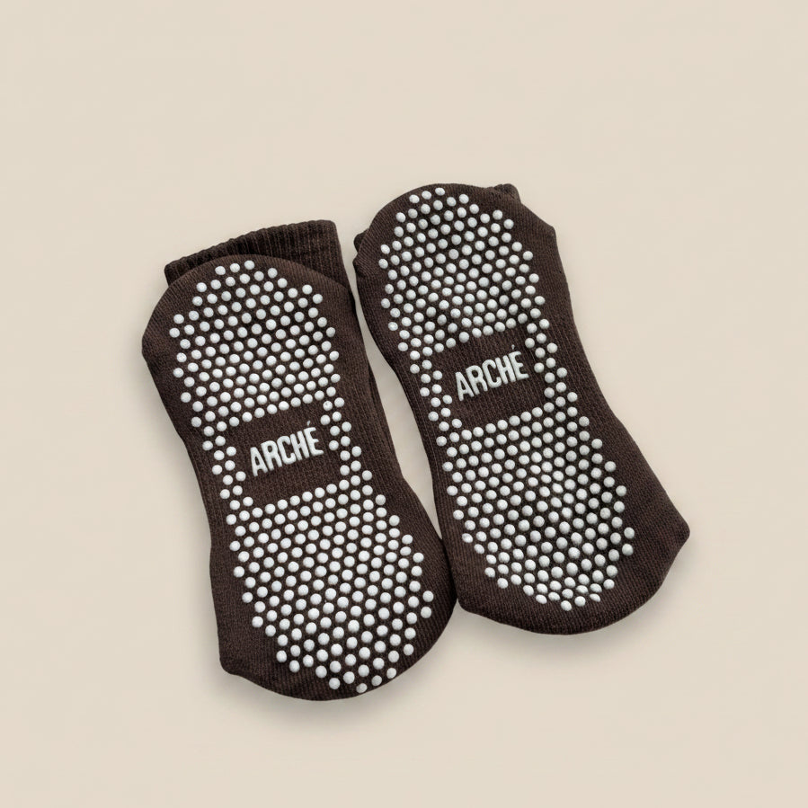 Sole view of dark brown ARCHÉ crew Pilates grip socks with white full-sole non-slip grip dots.