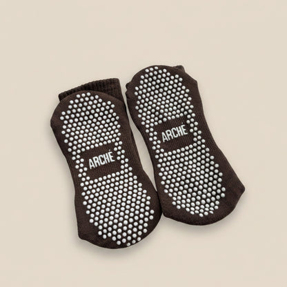 Sole view of dark brown ARCHÉ crew Pilates grip socks with white full-sole non-slip grip dots.