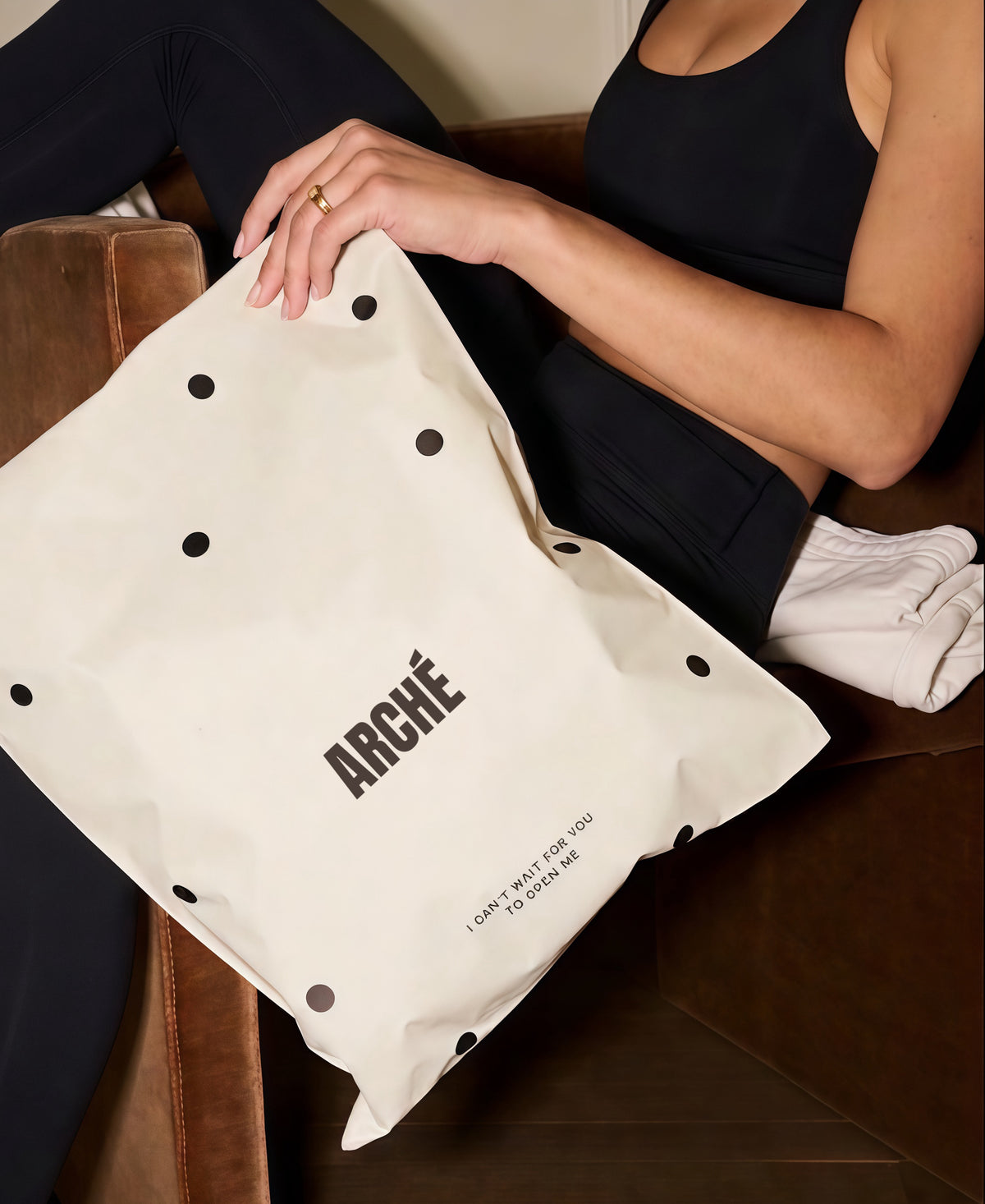 Woman holding ARCHÉ packaging while wearing white non-slip Pilates grip socks for yoga and barre.