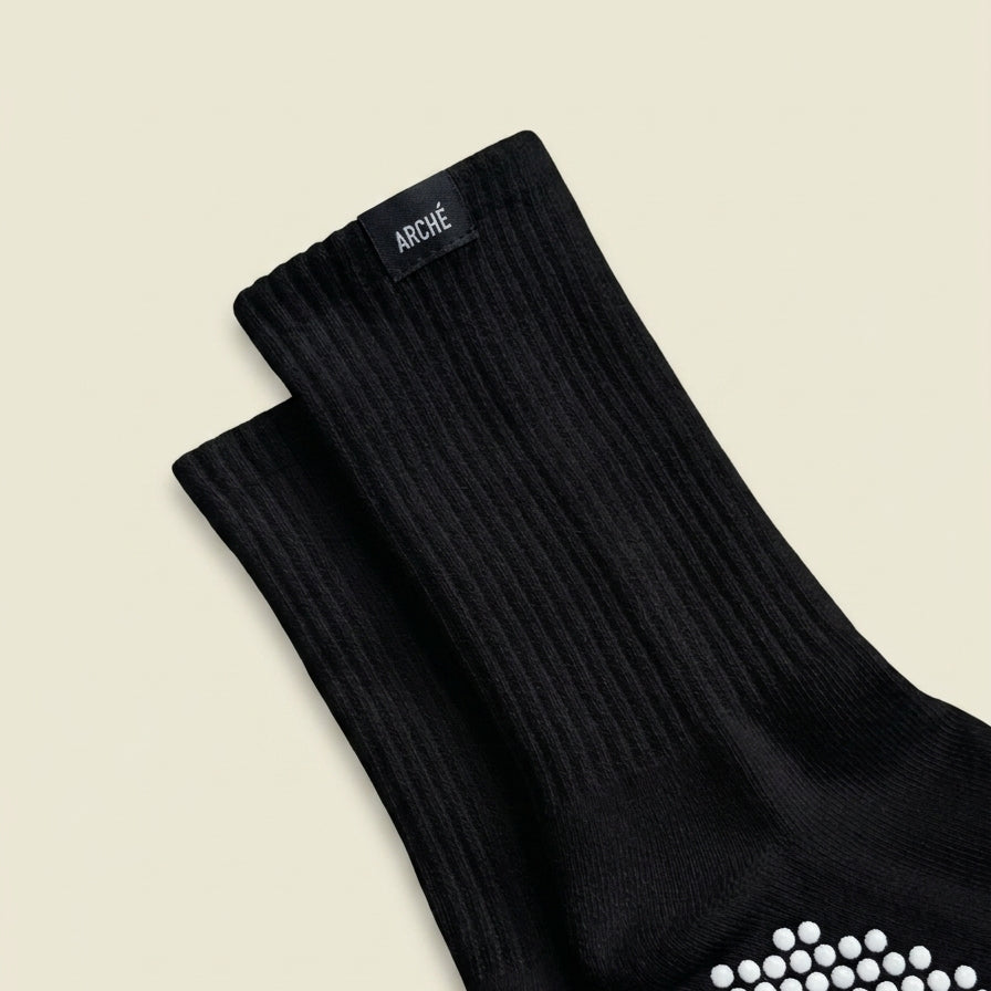 Close-up of black ARCHÉ ribbed crew Pilates grip socks with white non-slip sole grips