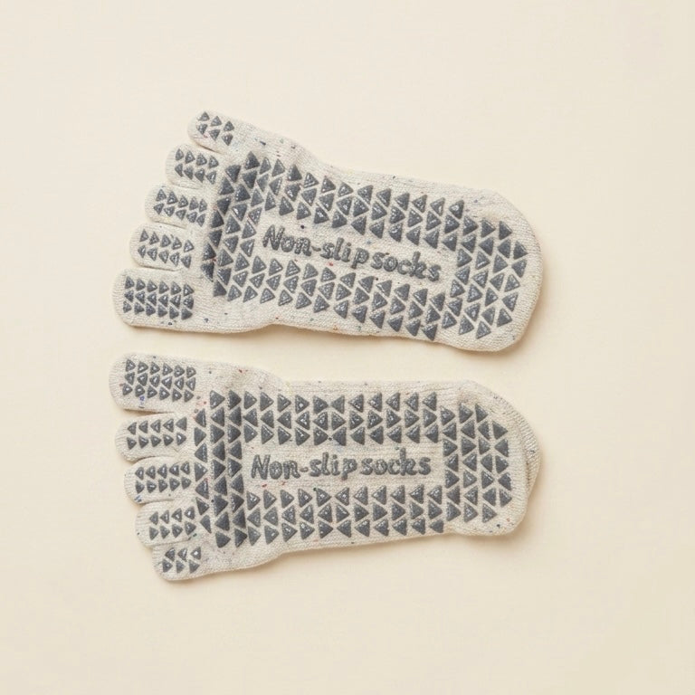 Bottom view of ARCHE ivory five-toe Pilates grip socks featuring textured non-slip grips across the soles for added traction during reformer and studio workouts