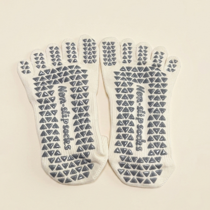Bottom view of ARCHE cream five-toe grip socks featuring full-sole non-slip grips for added traction during studio workouts.