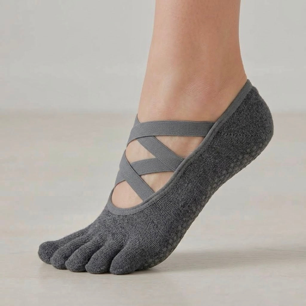 ARCHE graphite grey ballet-inspired five-toe grip socks worn on foot, featuring criss-cross straps and a non-slip sole for Pilates, yoga, barre and studio workouts.