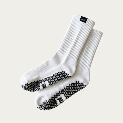 White ARCHÉ crew Pilates grip socks with black non-slip sole grips for yoga, barre and studio workouts.