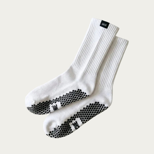 White ARCHÉ crew Pilates grip socks with black non-slip sole grips for yoga, barre and studio workouts.