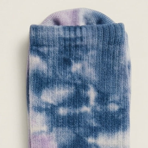 Close-up of muted sky blue tie-dye Pilates grip socks with ribbed crew construction and soft blue lavender studio style.